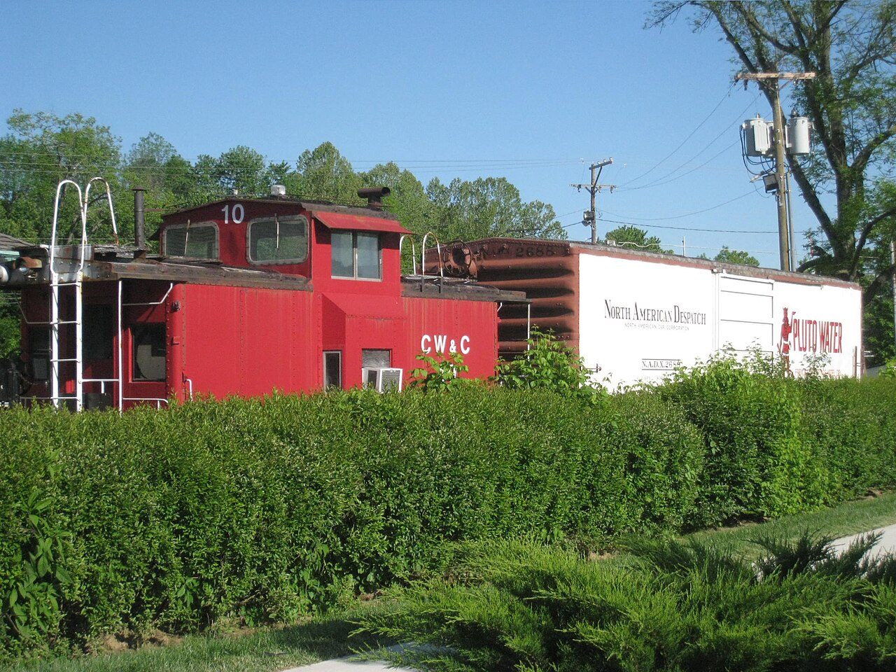 A red caboose from the French Lick Scenic Railway parked beside green hedges in French Lick, Indiana