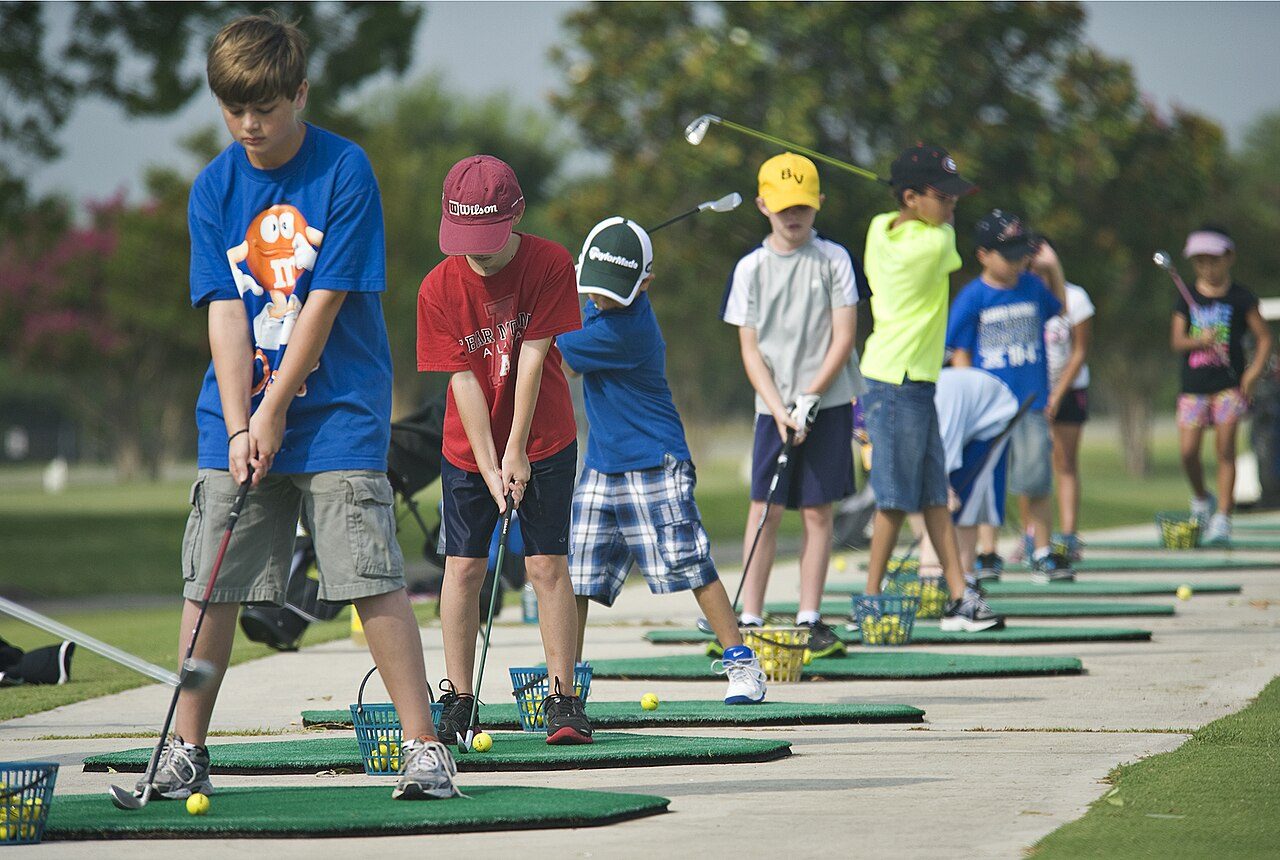 Children practicing their swings at a junior golf clinic driving range