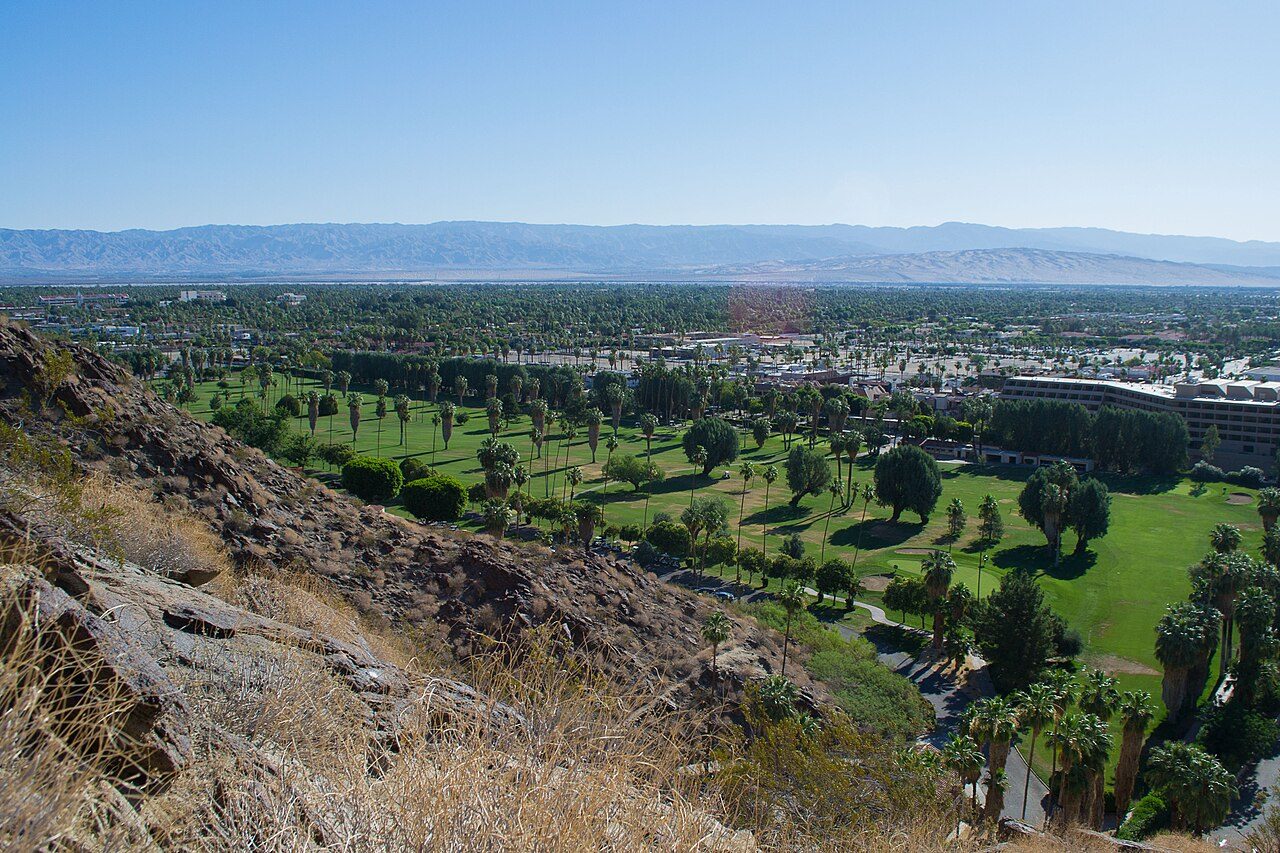 Green fairways on the valley floor at Palm Springs, seen from the rocky hills above the town