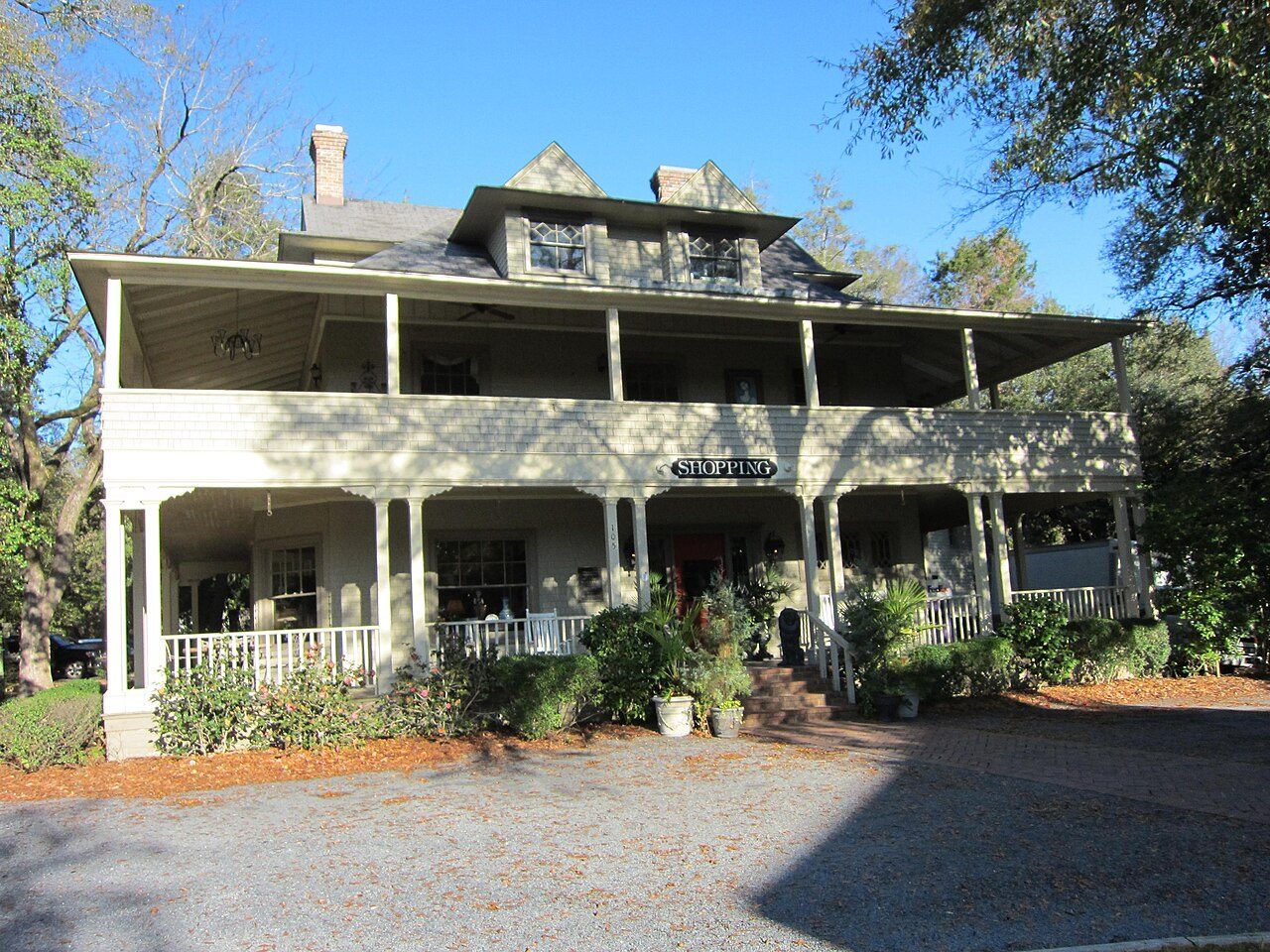 A two-story white cottage with a wide porch in the Village of Pinehurst