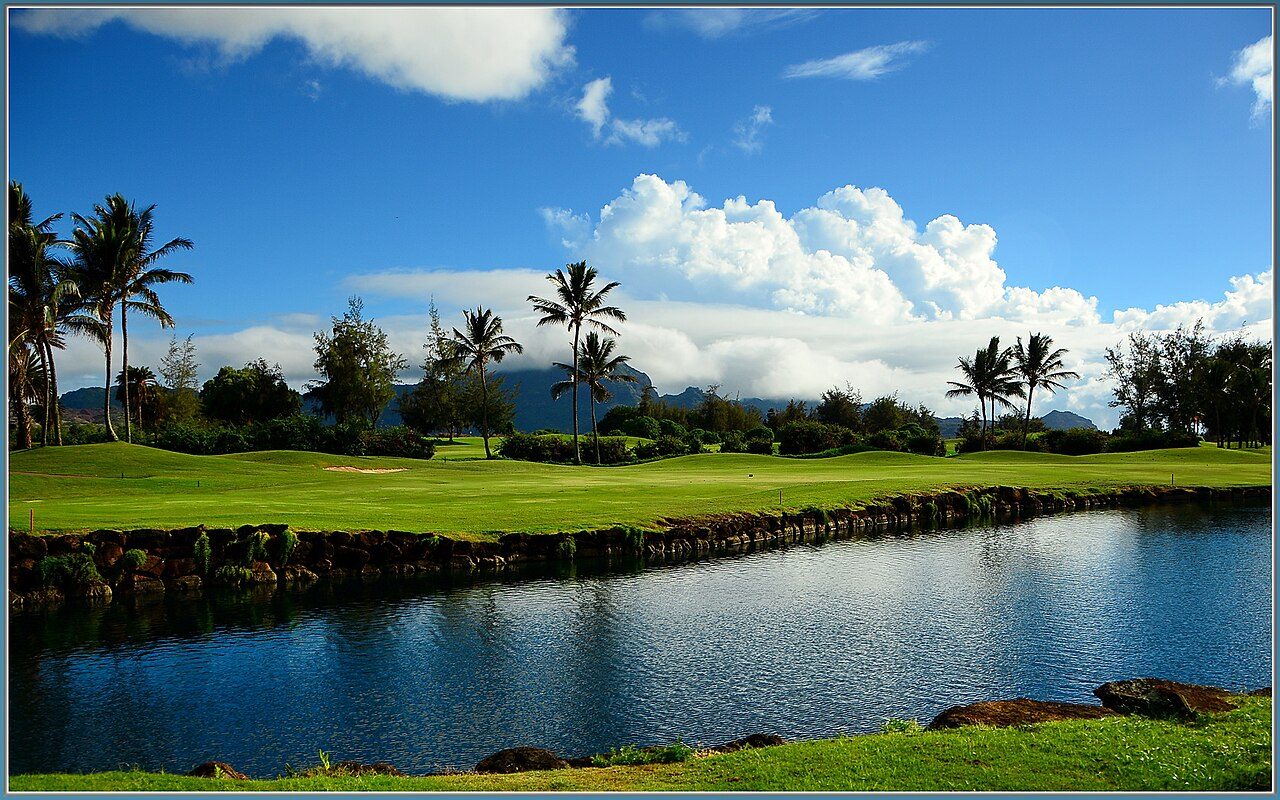 The Poipu Bay golf course on Kauai, with a lagoon, palms and mountains beyond