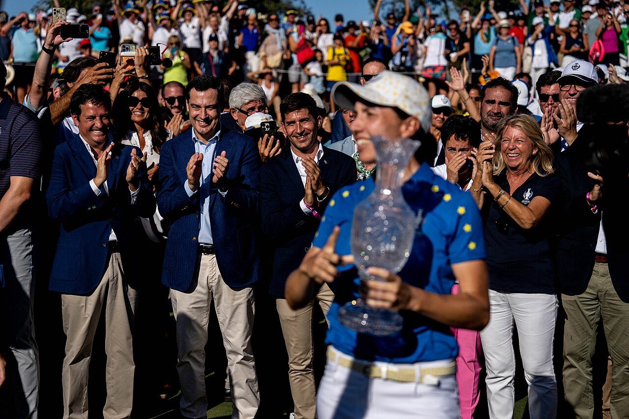 Carlota Ciganda holds the Solheim Cup trophy as teammates and fans applaud at the 2023 Solheim Cup