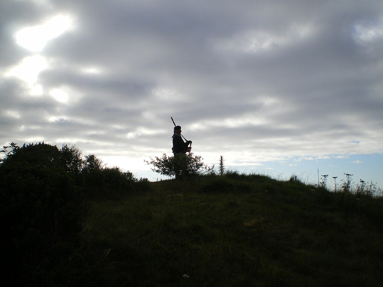 A bagpiper silhouetted on a dune at The Links at Spanish Bay at sunset