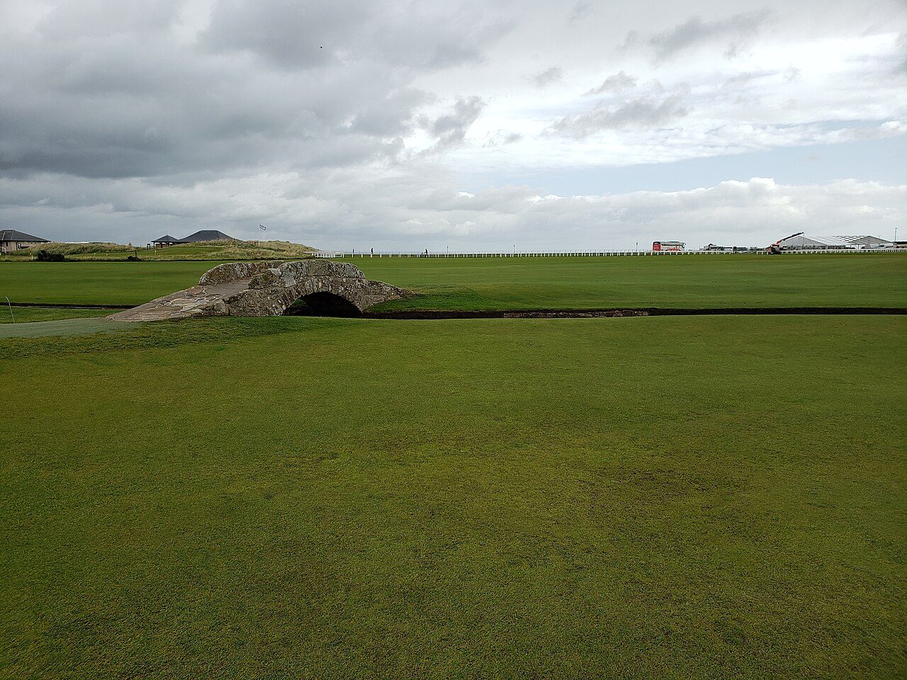 The Swilcan Bridge on the Old Course at St Andrews, with the 18th fairway and town beyond