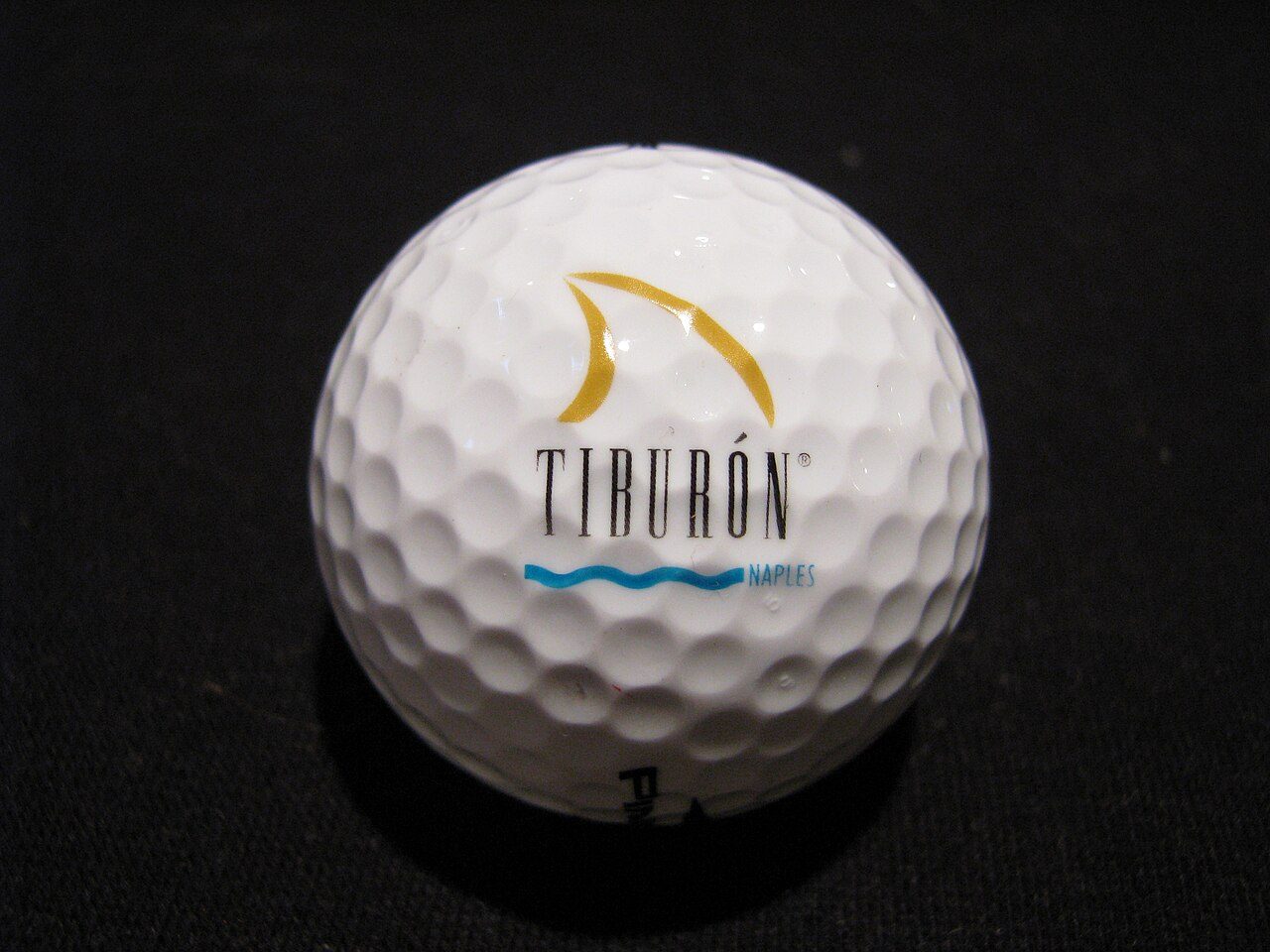 A white golf ball printed with the Tiburón logo, from the Ritz-Carlton golf club in Naples, Florida