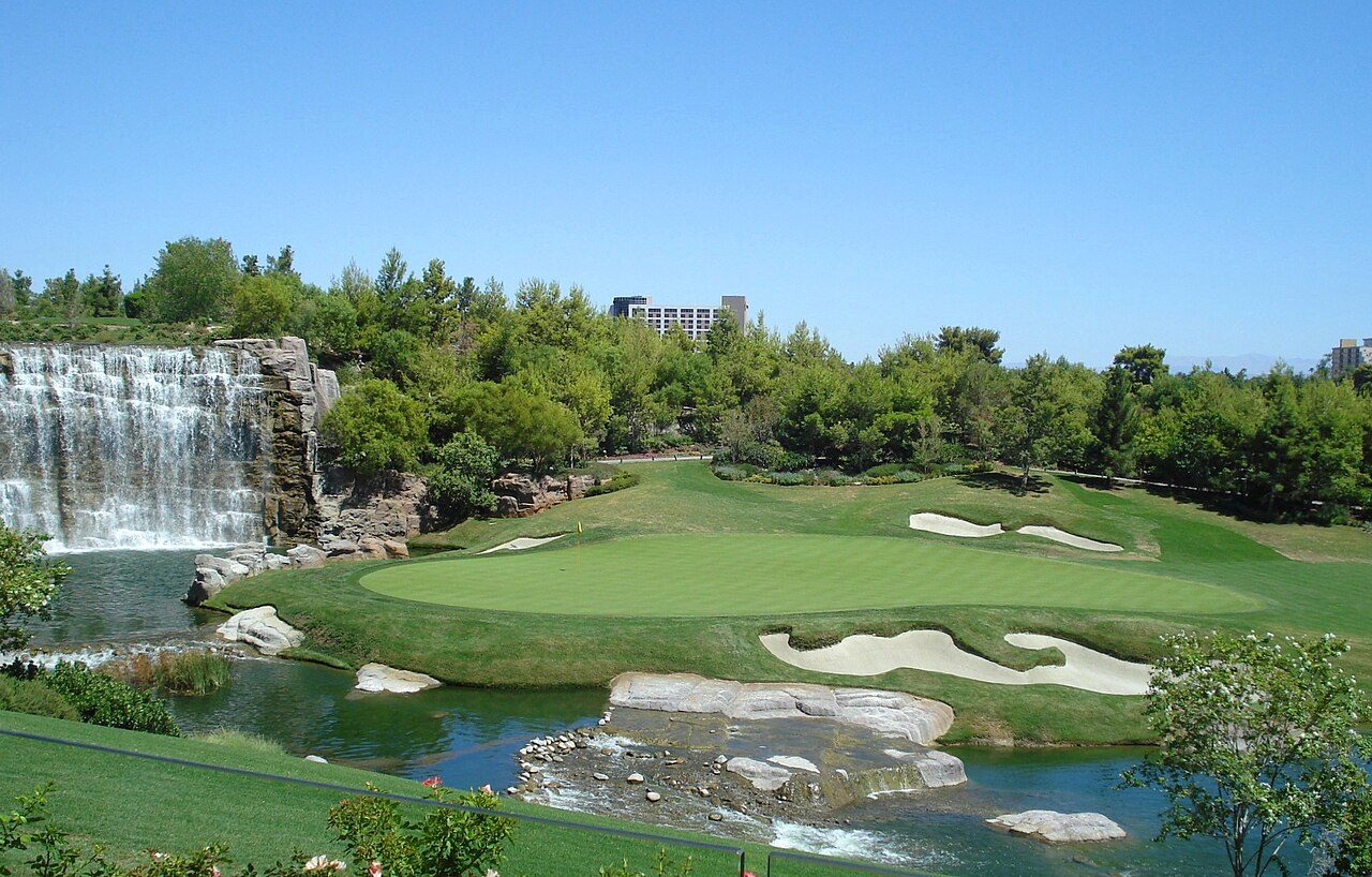 A waterfall and a green framed by bunkers and trees on the golf course at the Wynn resort in Las Vegas