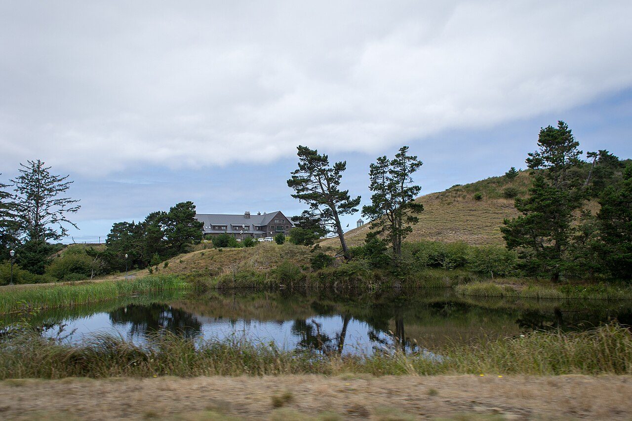 A pond below a resort building at Bandon Dunes, with shore pines on the dunes