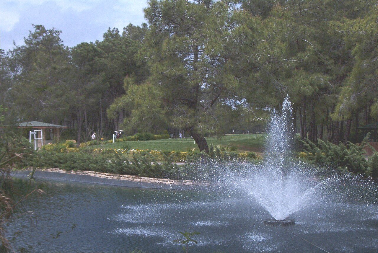 A pond and fountain in front of a fairway at the Gloria golf course in Belek, Turkey