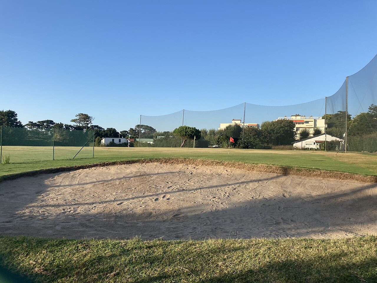 A practice bunker in front of a netted driving range