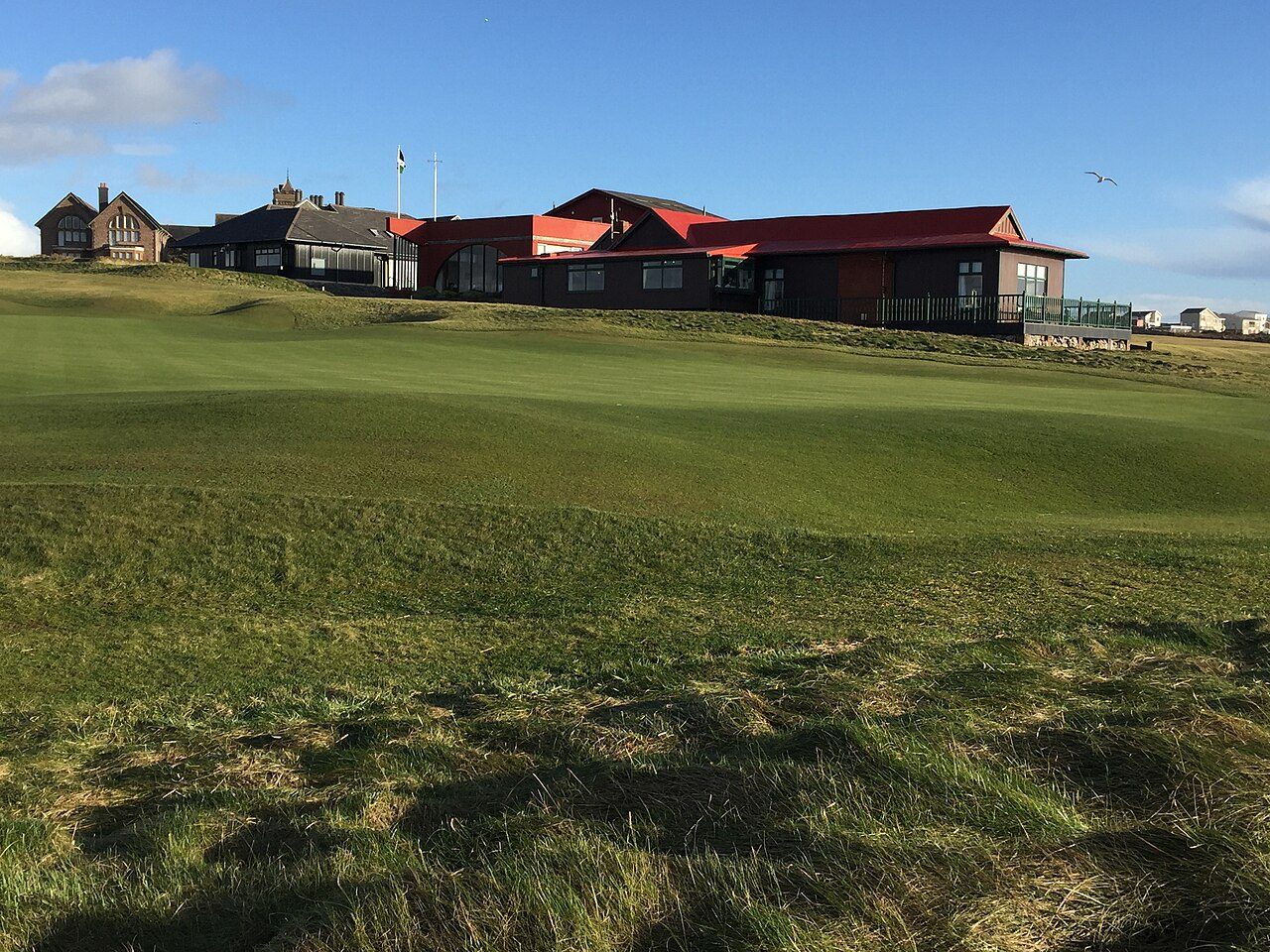 The clubhouse at Royal Porthcawl Golf Club behind a links fairway in south Wales