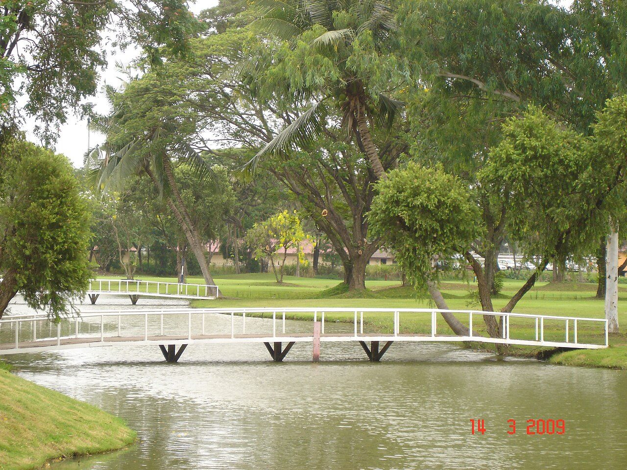 A footbridge over a water hazard on a tree-lined golf course near Bangkok, Thailand
